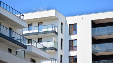 Modern mimarinin bir parçası, duvarlar ve cam. Mavi gökyüzüne karşı bir apartmanın pencere ve balkonları. New Lüks Ev ve Ev Kompleksinin ayrıntıları. Şehir gayrimenkul ve konut mimarisinin bir parçası..  