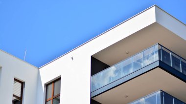 Modern mimarinin bir parçası, duvarlar ve cam. Mavi gökyüzüne karşı bir apartmanın pencere ve balkonları. New Lüks Ev ve Ev Kompleksinin ayrıntıları. Şehir gayrimenkul ve konut mimarisinin bir parçası..  