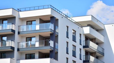 Modern mimarinin bir parçası, duvarlar ve cam. Mavi gökyüzüne karşı bir apartmanın pencere ve balkonları. New Lüks Ev ve Ev Kompleksinin ayrıntıları. Şehir gayrimenkul ve konut mimarisinin bir parçası..  