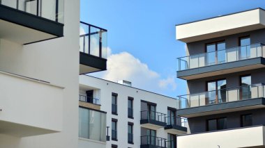 Modern mimarinin bir parçası, duvarlar ve cam. Mavi gökyüzüne karşı bir apartmanın pencere ve balkonları. New Lüks Ev ve Ev Kompleksinin ayrıntıları. Şehir gayrimenkul ve konut mimarisinin bir parçası..  