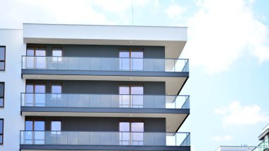 Modern mimarinin bir parçası, duvarlar ve cam. Mavi gökyüzüne karşı bir apartmanın pencere ve balkonları. New Lüks Ev ve Ev Kompleksinin ayrıntıları. Şehir gayrimenkul ve konut mimarisinin bir parçası..  