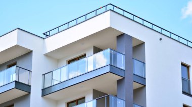 Modern mimarinin bir parçası, duvarlar ve cam. Mavi gökyüzüne karşı bir apartmanın pencere ve balkonları. New Lüks Ev ve Ev Kompleksinin ayrıntıları. Şehir gayrimenkul ve konut mimarisinin bir parçası..  