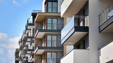 Modern mimarinin bir parçası, duvarlar ve cam. Mavi gökyüzüne karşı bir apartmanın pencere ve balkonları. New Lüks Ev ve Ev Kompleksinin ayrıntıları. Şehir gayrimenkul ve konut mimarisinin bir parçası..  