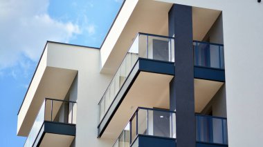 Modern mimarinin bir parçası, duvarlar ve cam. Mavi gökyüzüne karşı bir apartmanın pencere ve balkonları. New Lüks Ev ve Ev Kompleksinin ayrıntıları. Şehir gayrimenkul ve konut mimarisinin bir parçası..  