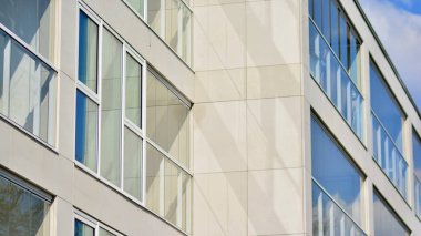 Modern mimarinin bir parçası, duvarlar ve cam. Mavi gökyüzüne karşı bir apartmanın pencere ve balkonları. New Lüks Ev ve Ev Kompleksinin ayrıntıları. Şehir gayrimenkul ve konut mimarisinin bir parçası..  