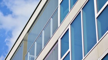 Modern mimarinin bir parçası, duvarlar ve cam. Mavi gökyüzüne karşı bir apartmanın pencere ve balkonları. New Lüks Ev ve Ev Kompleksinin ayrıntıları. Şehir gayrimenkul ve konut mimarisinin bir parçası..  