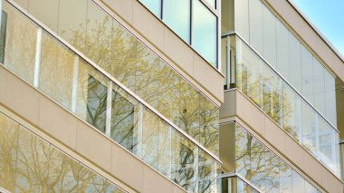 Modern mimarinin bir parçası, duvarlar ve cam. Mavi gökyüzüne karşı bir apartmanın pencere ve balkonları. New Lüks Ev ve Ev Kompleksinin ayrıntıları. Şehir gayrimenkul ve konut mimarisinin bir parçası..  