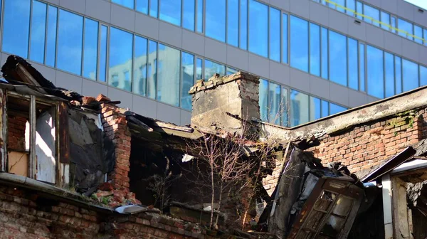 Yeni bir modern binanın arka planına karşı yıkım evi.