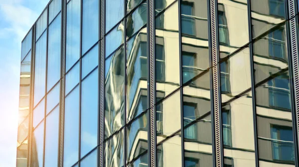 建物のガラスのファサードに青い空の反射 オフィスビルの窓の眺めは 日の出 展望とともに閉じます 青い空に太陽の光が差し込む明るい晴れた日のガラスのファサード — ストック写真