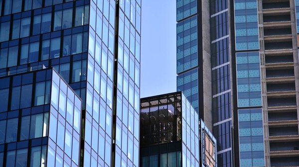 The glazed facade of an office building with reflected sky. Modern architecture buildings exterior background. Clouds sky reflection.