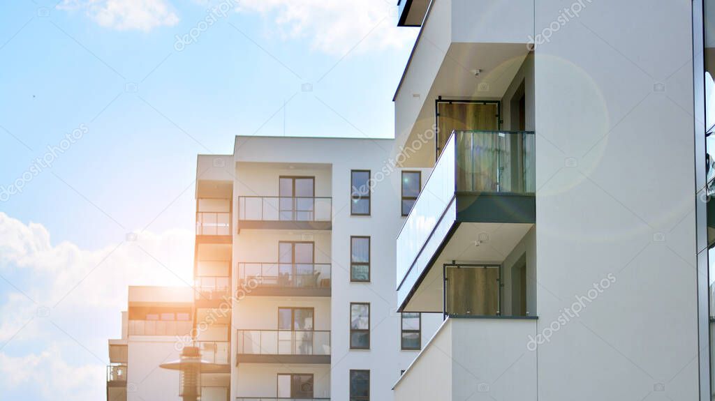 Detail of new luxury house and home complex. Glass surface with sunlight. Rising sun on the horizon. Part of modern residential apartment with flat building exterior. 