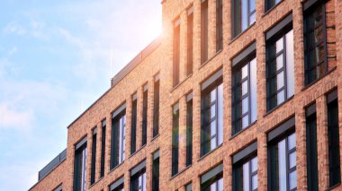 Ofis binasının modern tuğla ve cam cephesi. Bir bina üzerinde gökyüzü ve tuğla dokusunun zıt bir kombinasyonu. Kırmızı tuğlalı bir binanın mimari cephesi..