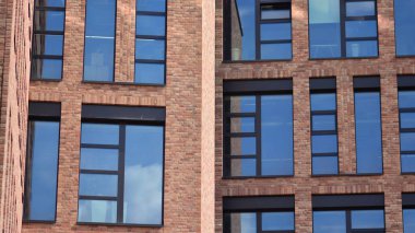 Ofis binasının modern tuğla ve cam cephesi. Bir bina üzerinde gökyüzü ve tuğla dokusunun zıt bir kombinasyonu. Kırmızı tuğlalı bir binanın mimari cephesi..
