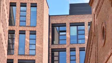 Ofis binasının modern tuğla ve cam cephesi. Bir bina üzerinde gökyüzü ve tuğla dokusunun zıt bir kombinasyonu. Kırmızı tuğlalı bir binanın mimari cephesi..