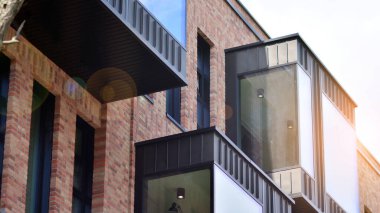 Ofis binasının modern tuğla ve cam cephesi. Bir bina üzerinde gökyüzü ve tuğla dokusunun zıt bir kombinasyonu. Kırmızı tuğlalı bir binanın mimari cephesi..