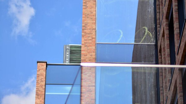 Modern brick and glass facade of the office building.  A contrasting combination of sky and brick texture on a building. Architectural facade of a red brick building..