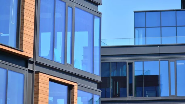 A fragment of the steel and glass metal facade of office building. Detail architecture steel and glass facade on clear blue sky background.  Modern architecture building facade.