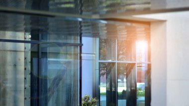 Güneş ışınlı modern mimari. Parlak güneşli bir günde mavi gökyüzünde güneş ışınları olan cam ve çelik cephe. Ekonomi, finans, iş faaliyeti kavramı.