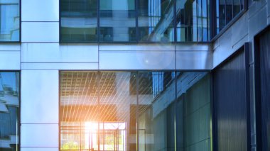 Güneş ışınlı modern mimari. Parlak güneşli bir günde mavi gökyüzünde güneş ışınları olan cam ve çelik cephe. Ekonomi, finans, iş faaliyeti kavramı.