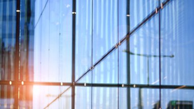Güneş ışınlı modern mimari. Parlak güneşli bir günde mavi gökyüzünde güneş ışınları olan cam ve çelik cephe. Ekonomi, finans, iş faaliyeti kavramı.