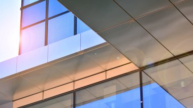 Güneş ışınlı modern mimari. Parlak güneşli bir günde mavi gökyüzünde güneş ışınları olan cam ve çelik cephe. Ekonomi, finans, iş faaliyeti kavramı.