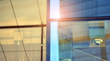 Güneş ışınlı modern mimari. Parlak güneşli bir günde mavi gökyüzünde güneş ışınları olan cam ve çelik cephe. Ekonomi, finans, iş faaliyeti kavramı.