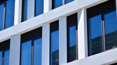 Modern bir beyaz ofis binasının parçası. Modern binanın ön cephesi. Pencerelerde gökyüzünün yansıması. Soyut mavi mimari arkaplan.
