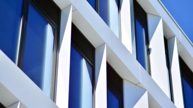 Modern bir beyaz ofis binasının parçası. Modern binanın ön cephesi. Pencerelerde gökyüzünün yansıması. Soyut mavi mimari arkaplan.