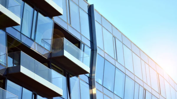 Modern glass building and rising sun. Glass facade on a bright sunny day with sunbeams in the blue sky. Economy, finances, business activity concept.