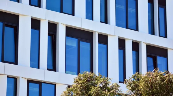 Modern bir beyaz ofis binasının parçası. Modern binanın ön cephesi. Pencerelerde gökyüzünün yansıması. Soyut mavi mimari arkaplan.