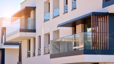 Apartman, ev ve dış görünüş mimarisi ve açık hava tesisleri. Çok katlı modern, yeni ve şık apartman daireleri. Arka planda mavi gökyüzü. Gün doğumunda gün ışığı.