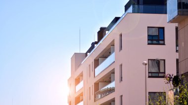 Apartman, ev ve dış görünüş mimarisi ve açık hava tesisleri. Çok katlı modern, yeni ve şık apartman daireleri. Arka planda mavi gökyüzü. Gün doğumunda gün ışığı.