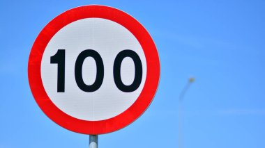 Otoyoldaki yol işareti saatte 100 km hız limitini gösteriyor. Beyaz merkezli kırmızı daire.