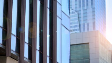 Güneş ışınlı modern mimari. Parlak güneşli bir günde mavi gökyüzünde güneş ışınları olan cam ve çelik cephe. Ekonomi, finans, iş faaliyeti kavramı.