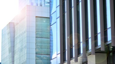 Güneş ışınlı modern mimari. Parlak güneşli bir günde mavi gökyüzünde güneş ışınları olan cam ve çelik cephe. Ekonomi, finans, iş faaliyeti kavramı.