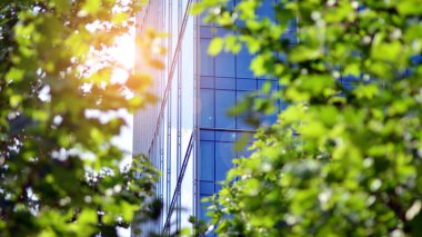 Güneş ışınlı modern mimari. Parlak güneşli bir günde mavi gökyüzünde güneş ışınları olan cam ve çelik cephe. Ekonomi, finans, iş faaliyeti kavramı.