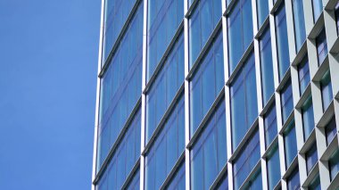 Yansıtıcı camlarla kaplı modern bir binanın cam kaplamalı dış cephesinin soyut yakın çekimi. Mimari soyut arkaplan. Cam duvar ve ön cephe ayrıntıları.