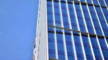 Yansıtıcı camlarla kaplı modern bir binanın cam kaplamalı dış cephesinin soyut yakın çekimi. Mimari soyut arkaplan. Cam duvar ve ön cephe ayrıntıları.