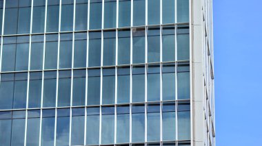 Yansıtıcı camlarla kaplı modern bir binanın cam kaplamalı dış cephesinin soyut yakın çekimi. Mimari soyut arkaplan. Cam duvar ve ön cephe ayrıntıları.