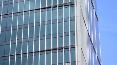 Yansıtıcı camlarla kaplı modern bir binanın cam kaplamalı dış cephesinin soyut yakın çekimi. Mimari soyut arkaplan. Cam duvar ve ön cephe ayrıntıları.