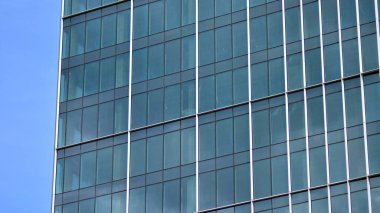 Yansıtıcı camlarla kaplı modern bir binanın cam kaplamalı dış cephesinin soyut yakın çekimi. Mimari soyut arkaplan. Cam duvar ve ön cephe ayrıntıları.
