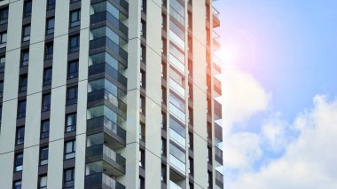 Mavi gökyüzü olan güneşli bir günde modern apartman binaları. Modern bir apartmanın ön cephesi. Güneş ışığıyla cam yüzey.