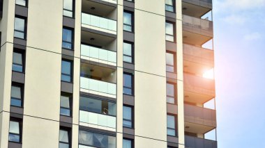 Mavi gökyüzü olan güneşli bir günde modern apartman binaları. Modern bir apartmanın ön cephesi. Güneş ışığıyla cam yüzey.
