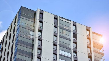 Mavi gökyüzü olan güneşli bir günde modern apartman binaları. Modern bir apartmanın ön cephesi. Güneş ışığıyla cam yüzey.