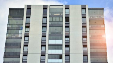Mavi gökyüzü olan güneşli bir günde modern apartman binaları. Modern bir apartmanın ön cephesi. Güneş ışığıyla cam yüzey.
