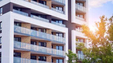 Mavi gökyüzü olan güneşli bir günde modern apartman binaları. Modern bir apartmanın ön cephesi. Güneş ışığıyla cam yüzey.