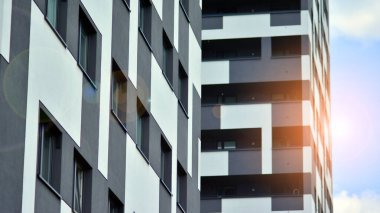 Mavi gökyüzü olan güneşli bir günde modern apartman binaları. Modern bir apartmanın ön cephesi. Güneş ışığıyla cam yüzey.
