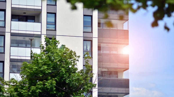 Mavi gökyüzü olan güneşli bir günde modern apartman binaları. Modern bir apartmanın ön cephesi. Güneş ışığıyla cam yüzey.