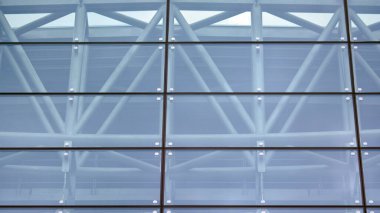 Yansıtıcı camlarla kaplı modern bir binanın cam kaplamalı dış cephesinin soyut yakın çekimi. Mimari soyut arkaplan. Cam duvar ve ön cephe ayrıntıları.