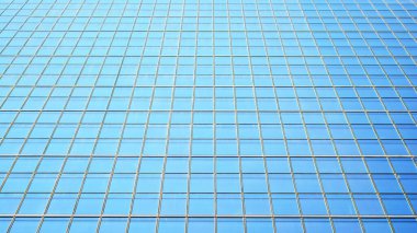 Mavi gökyüzü ve bulutlar modern ofis binasının camlarına yansıyor. Modern cam cephe. 